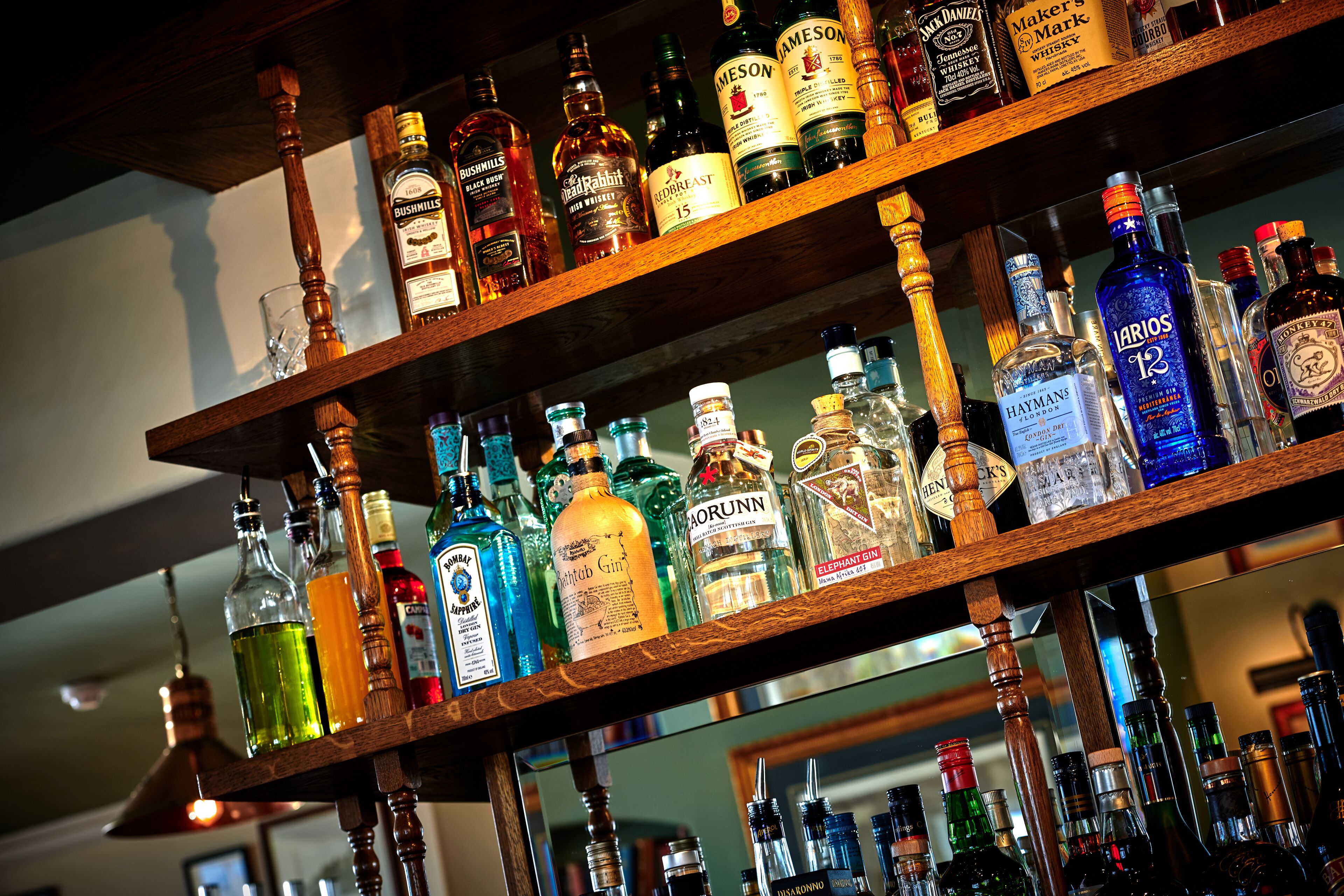 A bar with multiple shelves stocked with various liquor bottles.