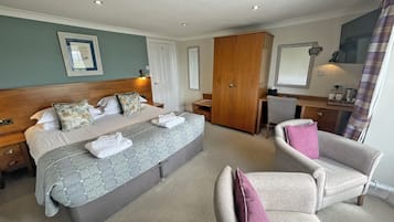Una habitación de hotel con una cama grande, un armario de madera, un escritorio con silla y un sofá.