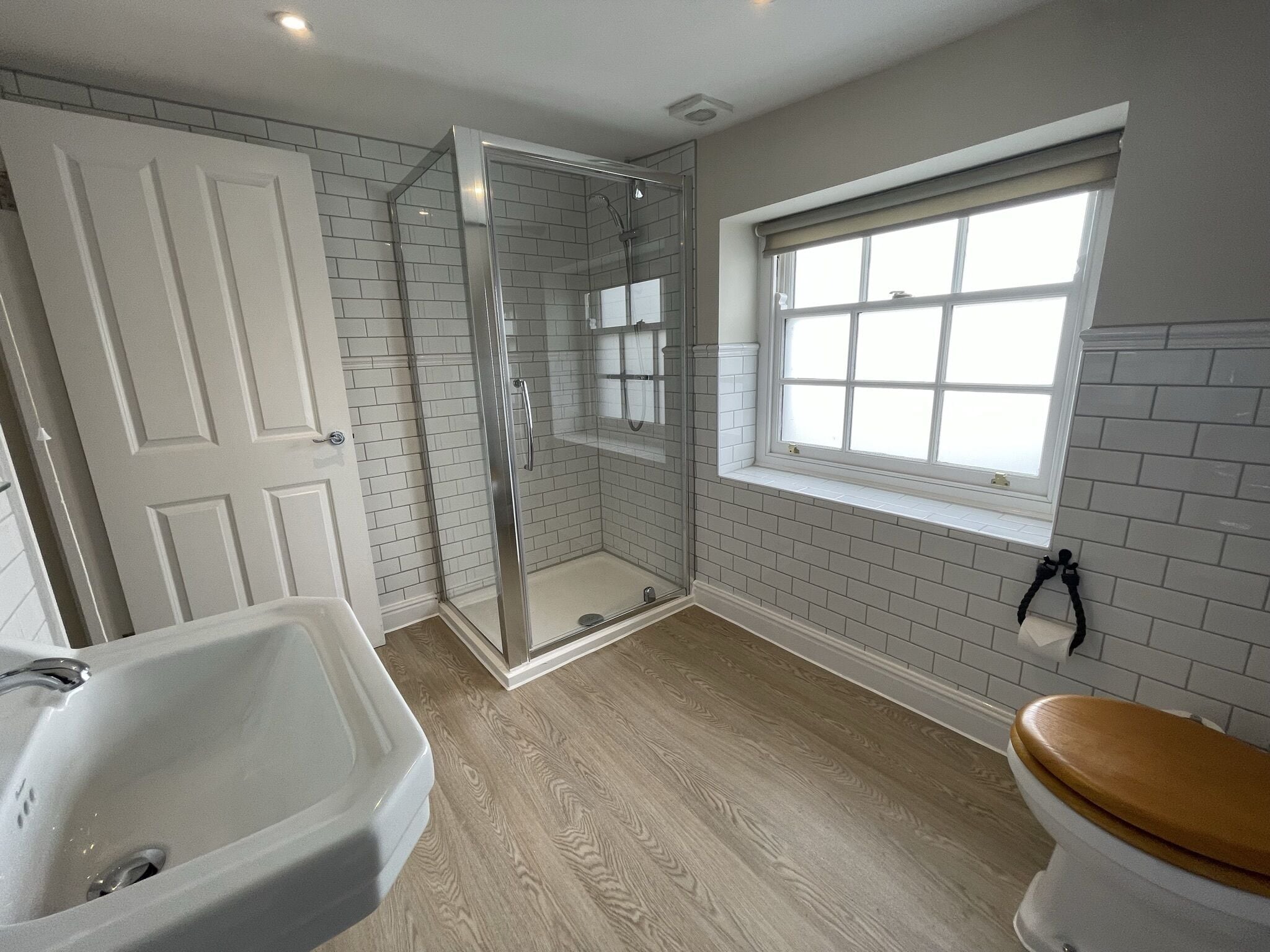 A bathroom with a glass-enclosed shower, a white bathtub, and a window with a view.