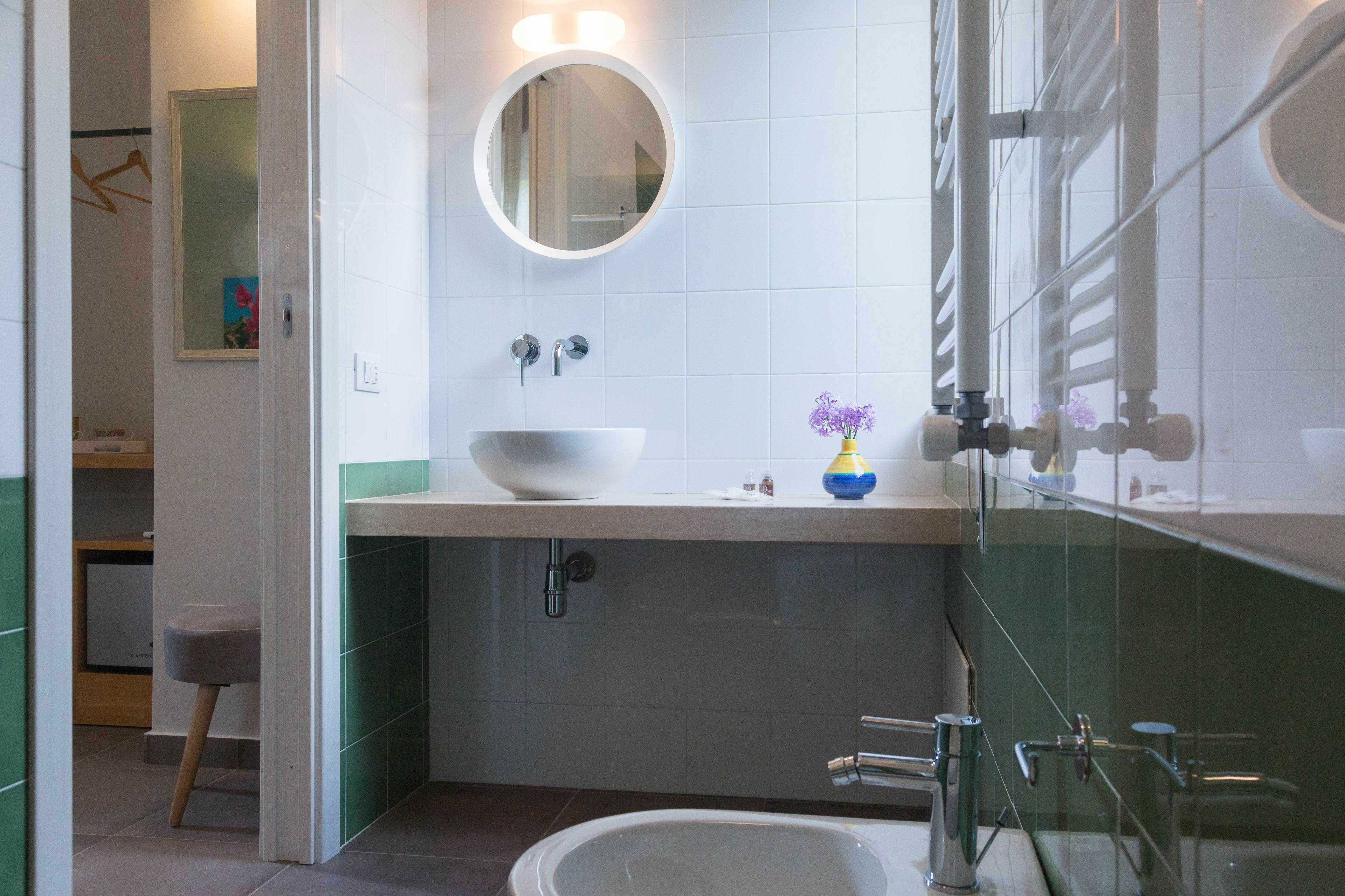 A modern bathroom with a white sink, a round mirror, and a glass shower enclosure.