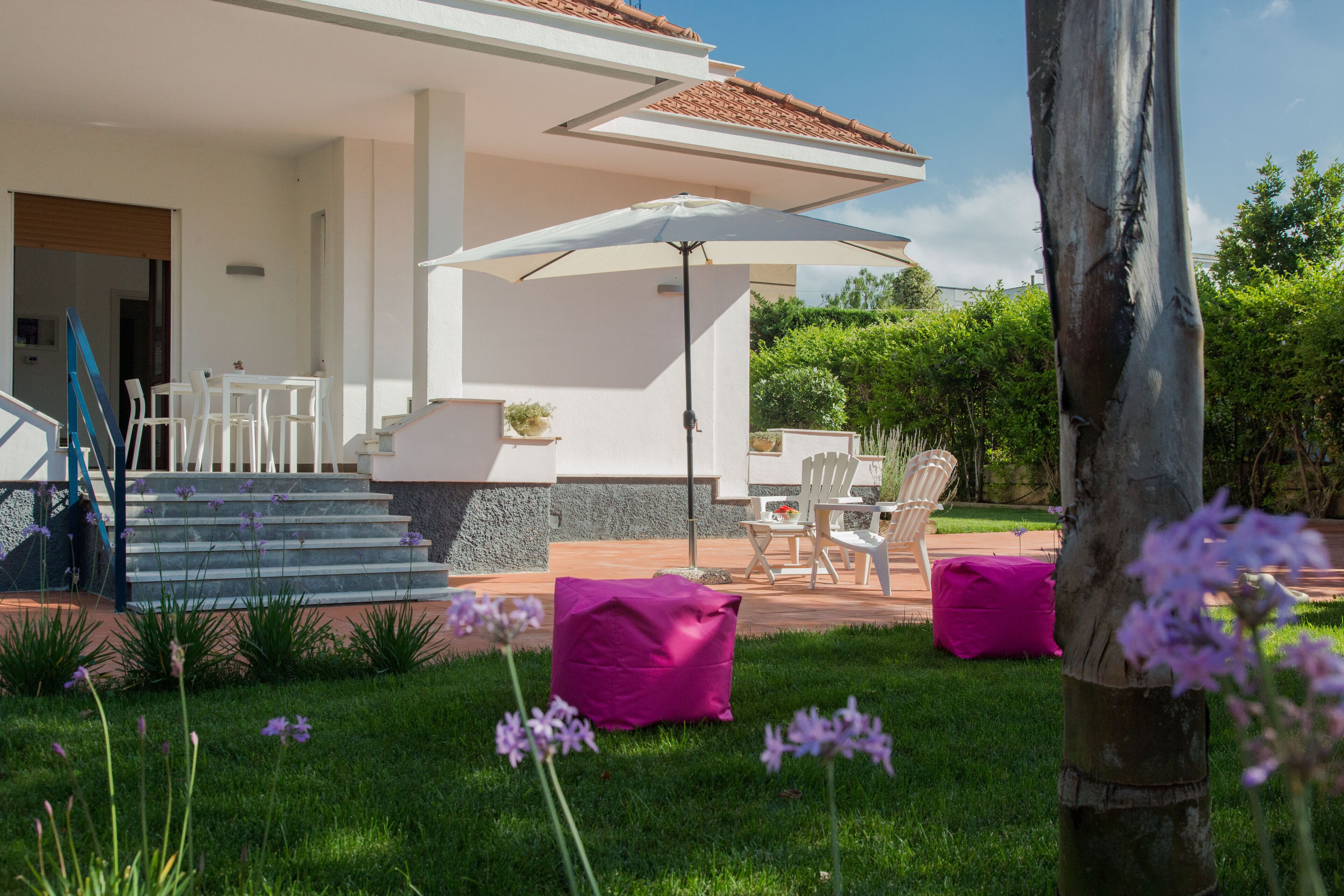 A modern house with a patio area, outdoor furniture, and a large umbrella.
