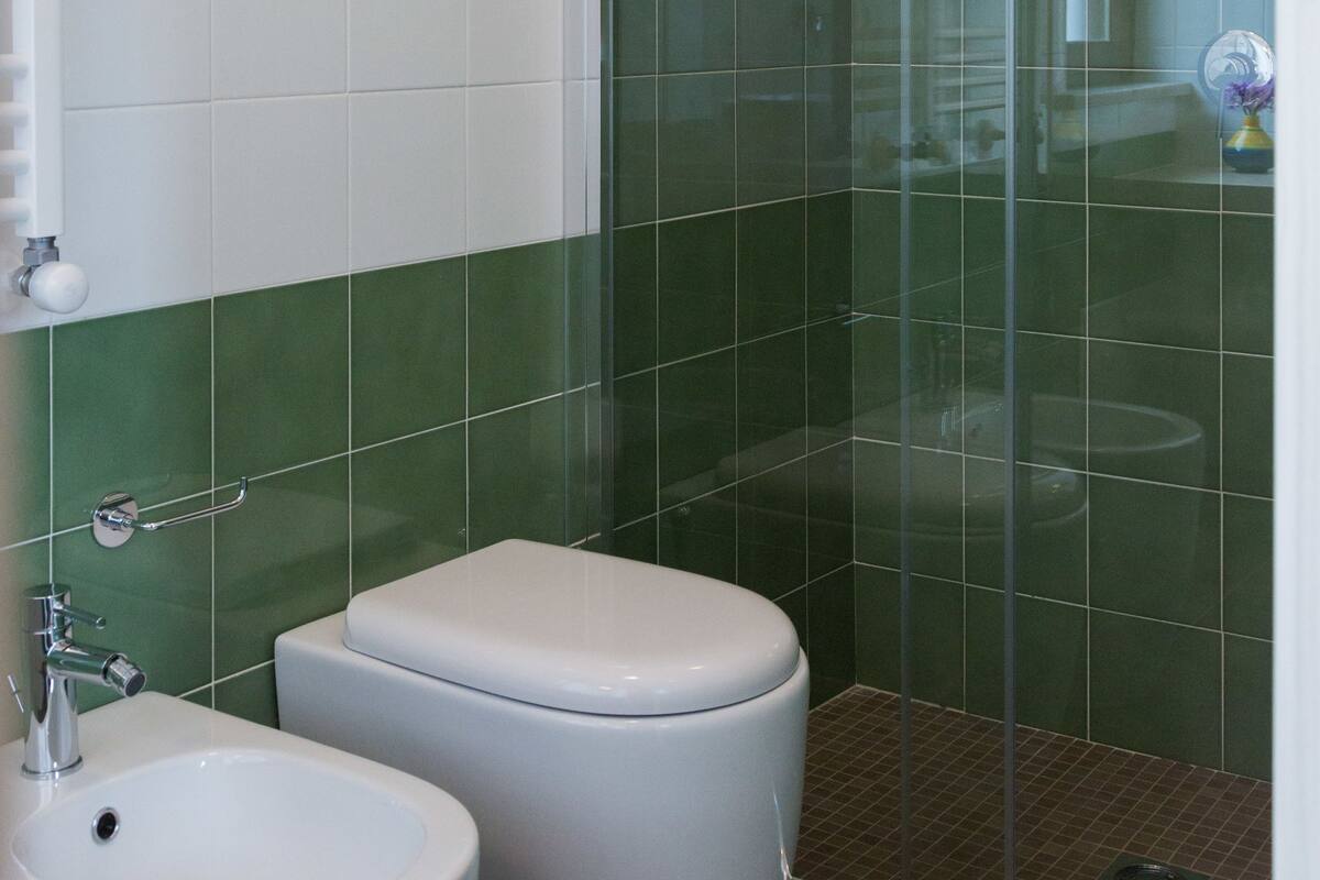 A bathroom with a glass-enclosed shower, a white sink, and a toilet.