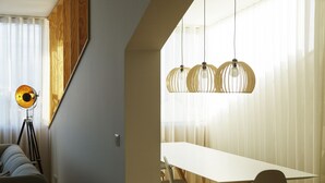 A dining area with a white table and chairs, a tripod floor lamp, and a hanging light fixture. - Praça 66 Guest House (Porto)