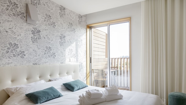 A hotel room with a large bed, a cityscape wallpaper, and a balcony with a view. - Praça 66 Guest House (Porto)