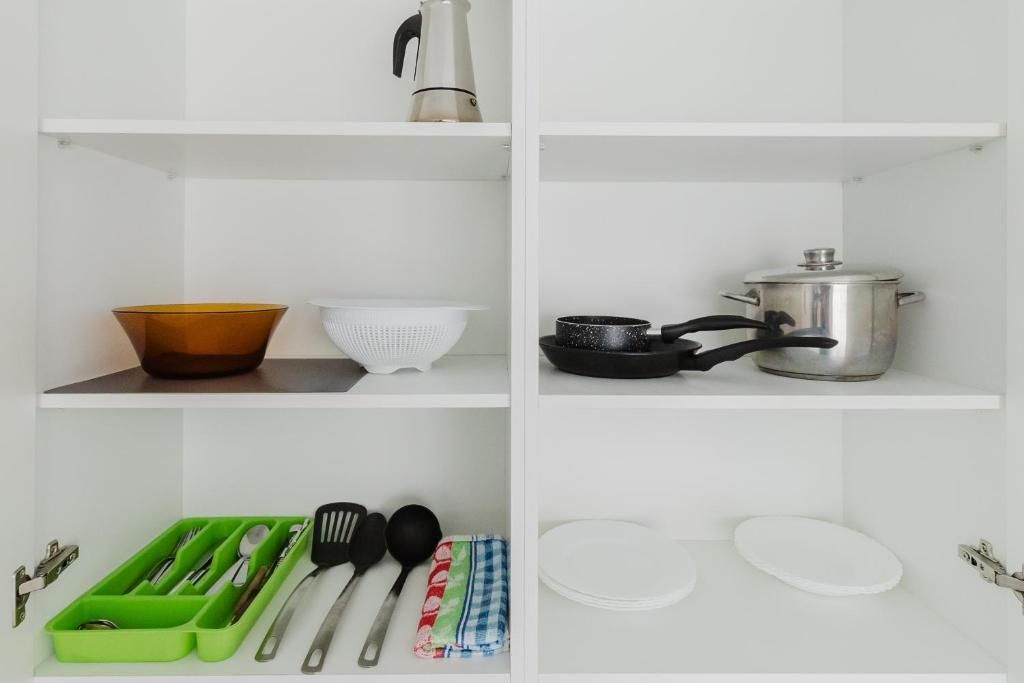 Un estante de cocina con una cafetera, una olla, una sartén y un colador.
