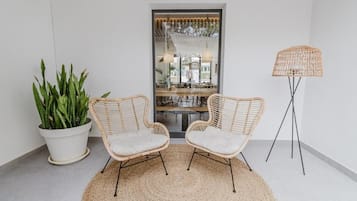 A room with two wicker chairs, a woven rug, a potted plant, and a floor lamp.