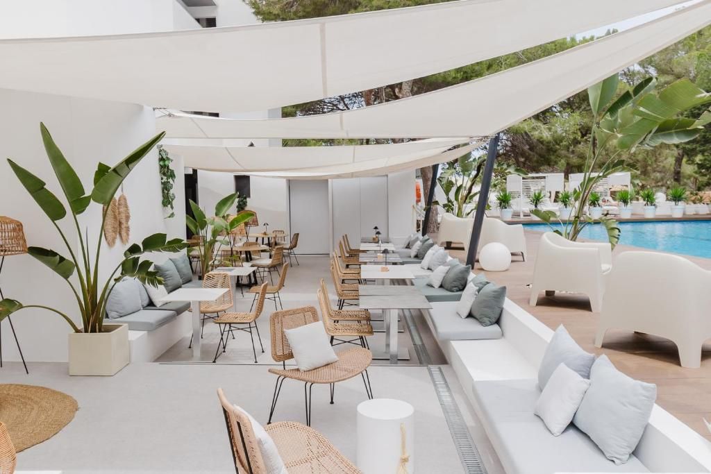 An outdoor seating area with tables and chairs, a pool, and potted plants.