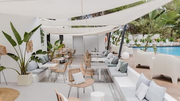 An outdoor seating area with tables and chairs, a pool, and potted plants.