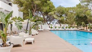 A poolside area with lounge chairs, potted plants, and a clear blue pool.
