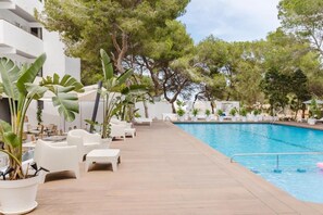A poolside area with lounge chairs, potted plants, and a clear blue pool. - Apartamentos Es Pujols (Formentera)