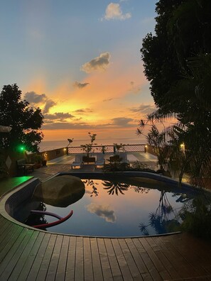 A pool area with lounge chairs and a view of the sunset over the ocean. - Memorial Ilhabela Residencial (Ilhabela)