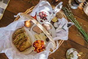 A wooden table with a variety of food items, including bread, cheese, fruit, and a bowl of yogurt with berries. - Mazaraki Guesthouse (Sparta)