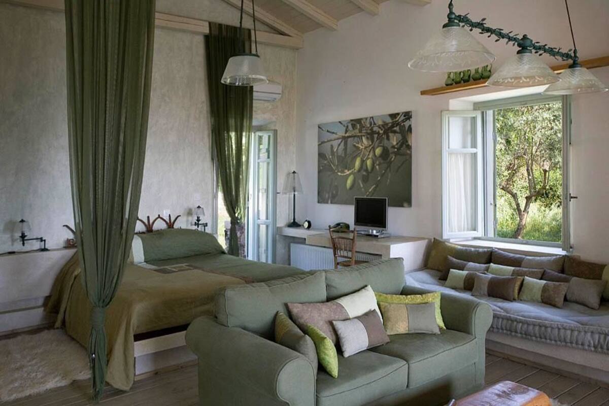 Ein Schlafzimmer mit Bett, Schreibtisch, Computer und einer Couch.