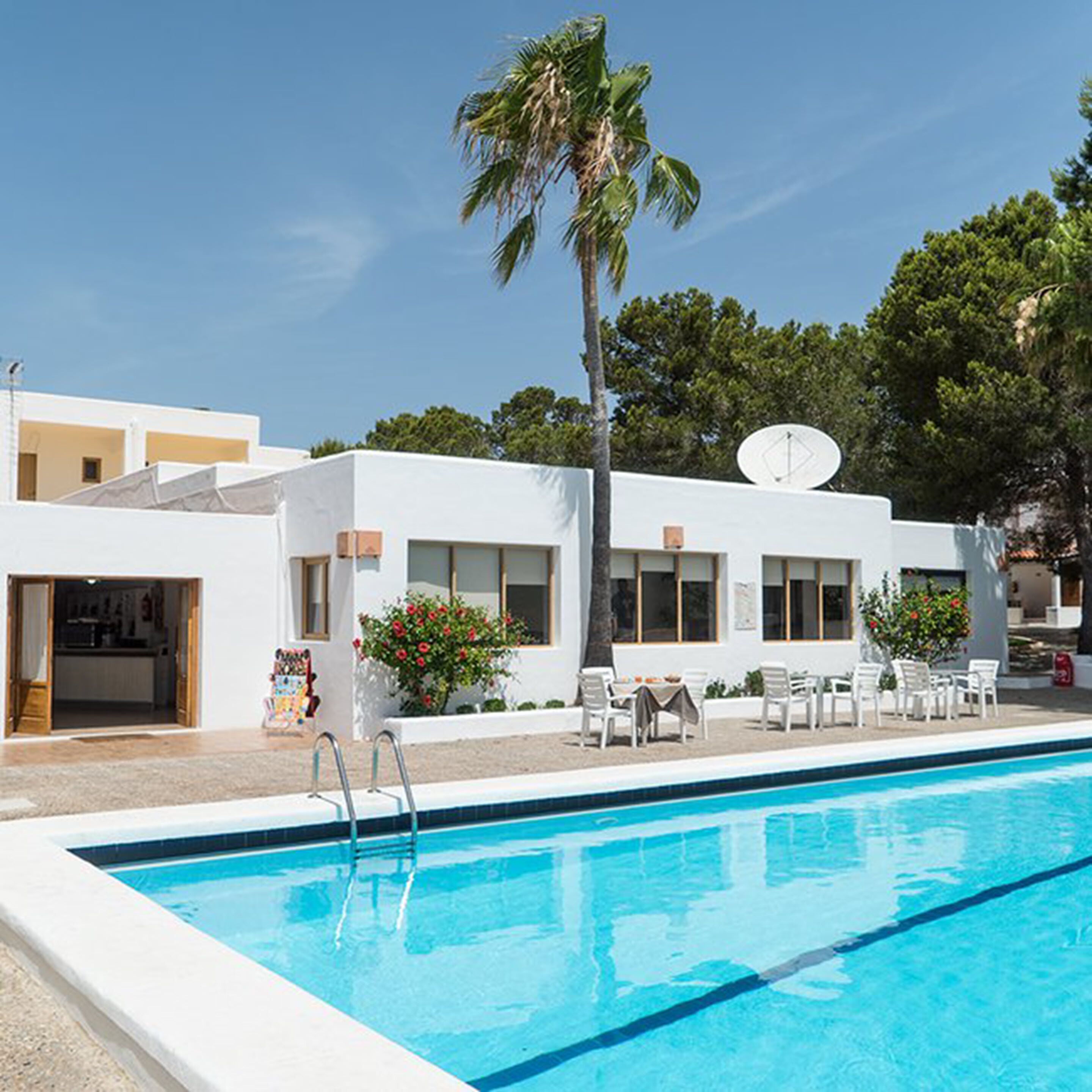 A modern building with a swimming pool, outdoor seating, and a satellite dish.