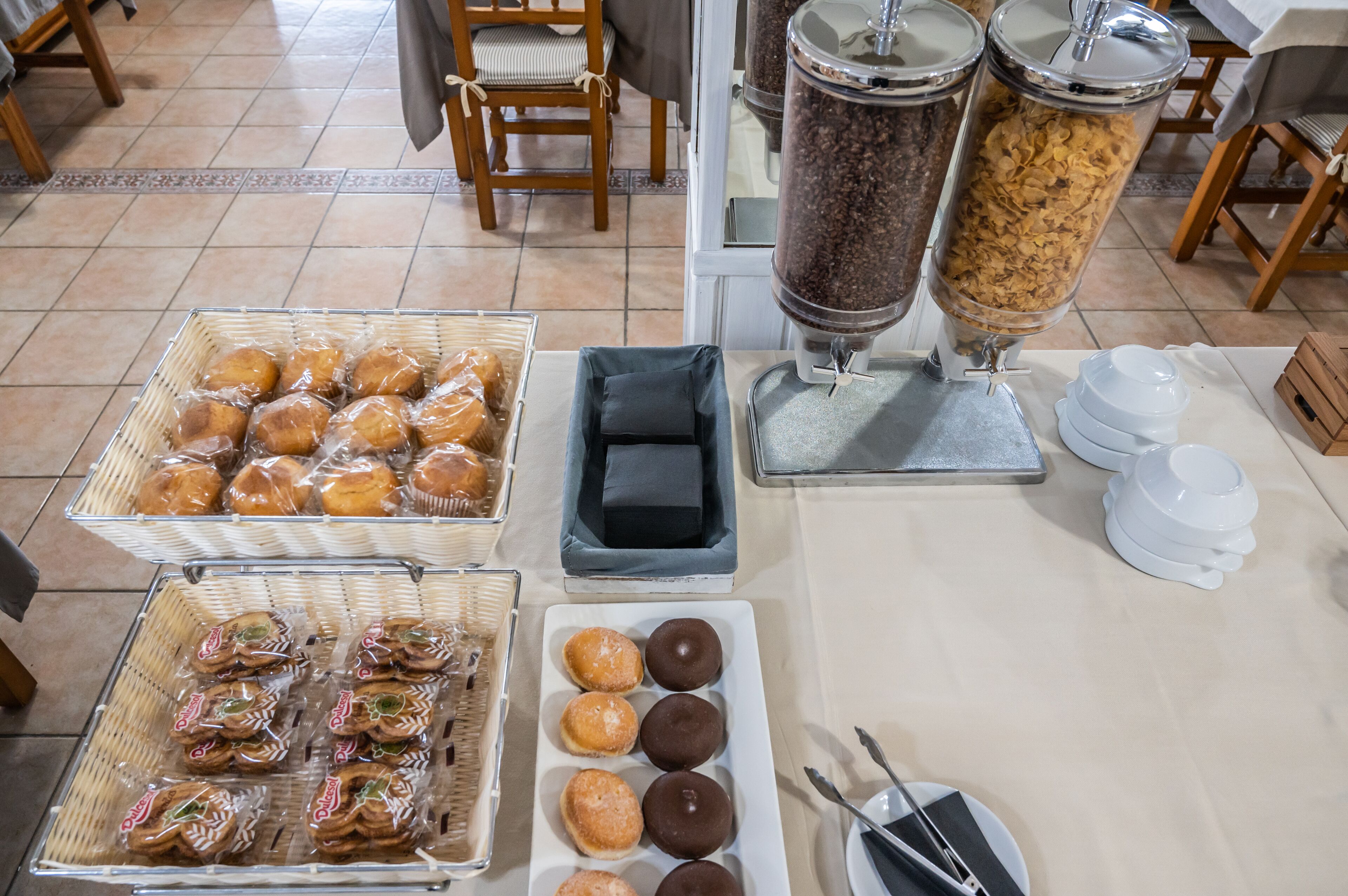 Een buffetopstelling met diverse soorten eten, waaronder gebak en donuts, op een tafel gerangschikt.