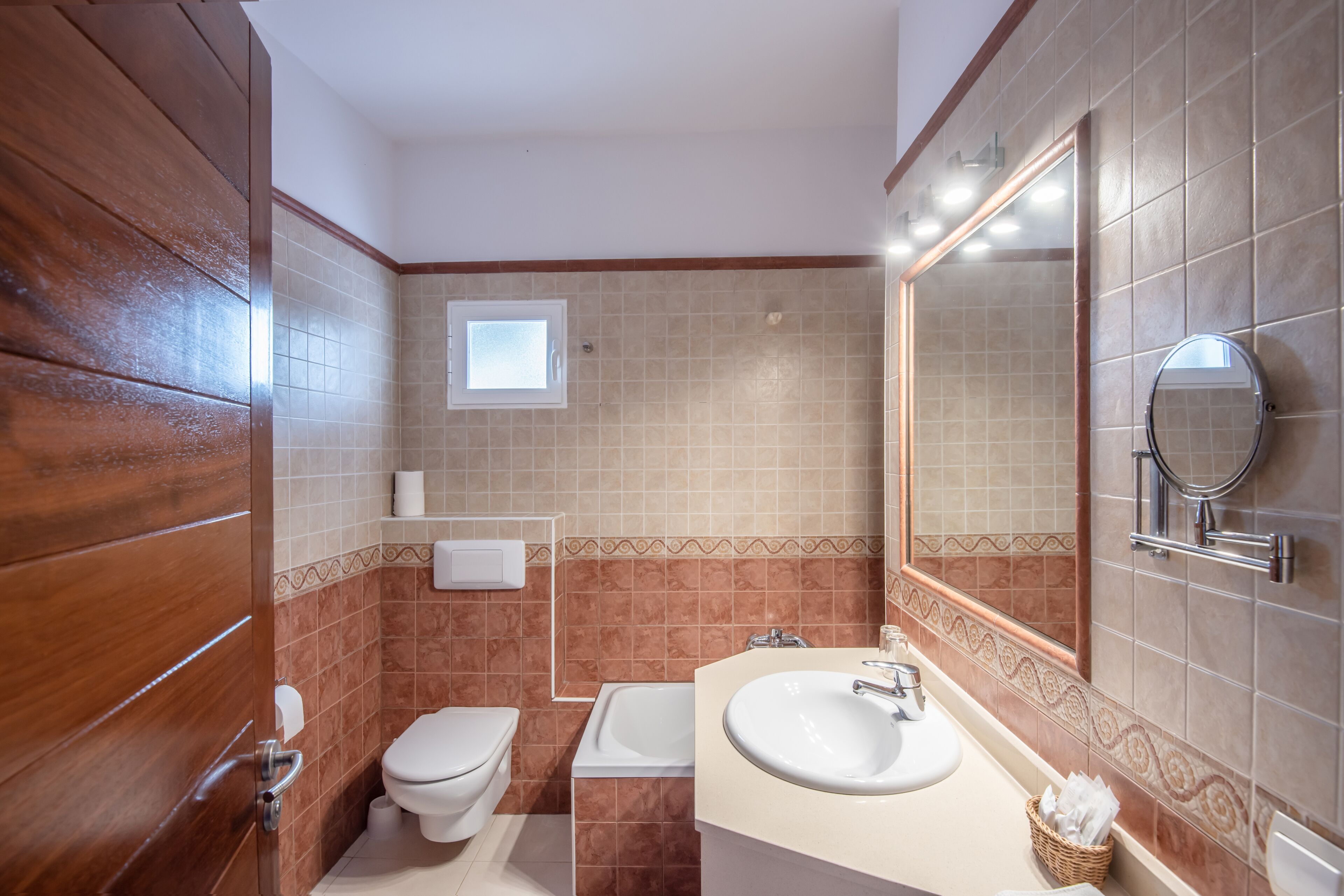 A bathroom with a wooden vanity, a sink, a toilet, and a bathtub.