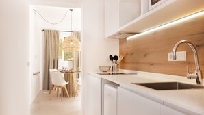 Una cocina moderna con armarios blancos, encimera de madera y pileta de acero inoxidable.