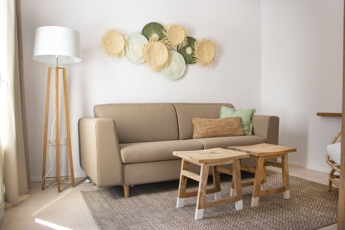 A living room with a beige sofa, two wooden side tables, a floor lamp, and a wall art piece.