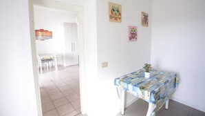 Een kamer met een eettafel, een kleine tafeltje met een plant, en kunst aan de muur.