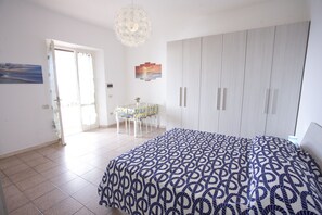 Une chambre à coucher comprenant un lit, une armoire, une table à manger avec des chaises et un lustre.