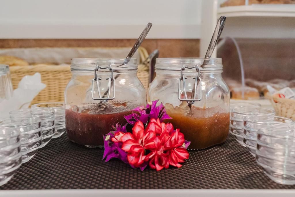 Dos frascos de vidrio con cierres metálicos, cada uno conteniendo una sustancia de diferente color, posiblemente alimentos, sobre una mesa con un mantel tejido.