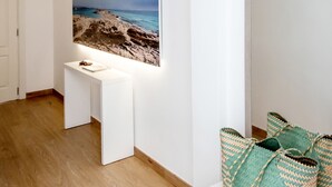 A modern room with a wooden floor, a white desk, a large framed picture of a beach, and a white wardrobe. - Hostal Es Pi (Formentera)