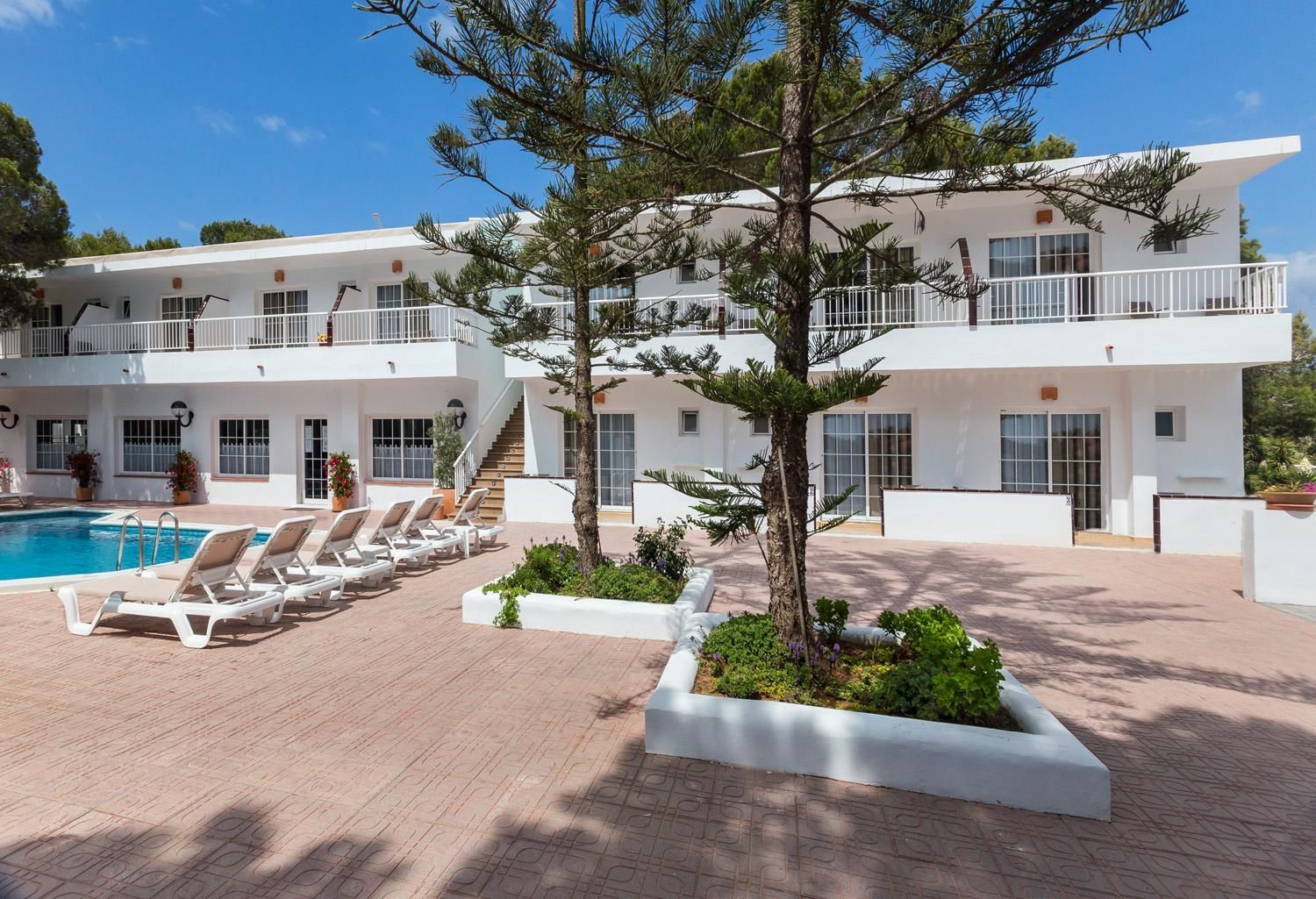 A modern hotel with a pool area, lounge chairs, and a staircase leading to the upper floors.