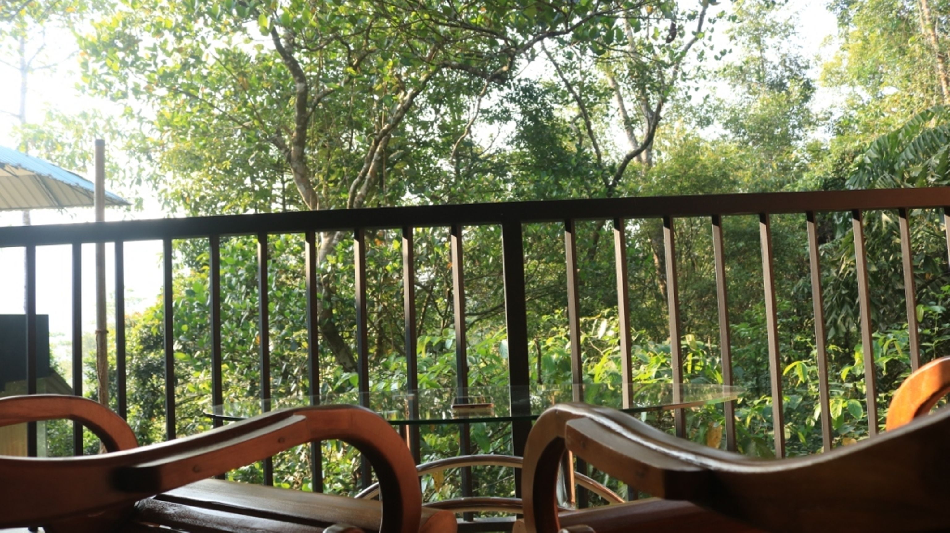 A balcony with metal railings and wooden chairs.