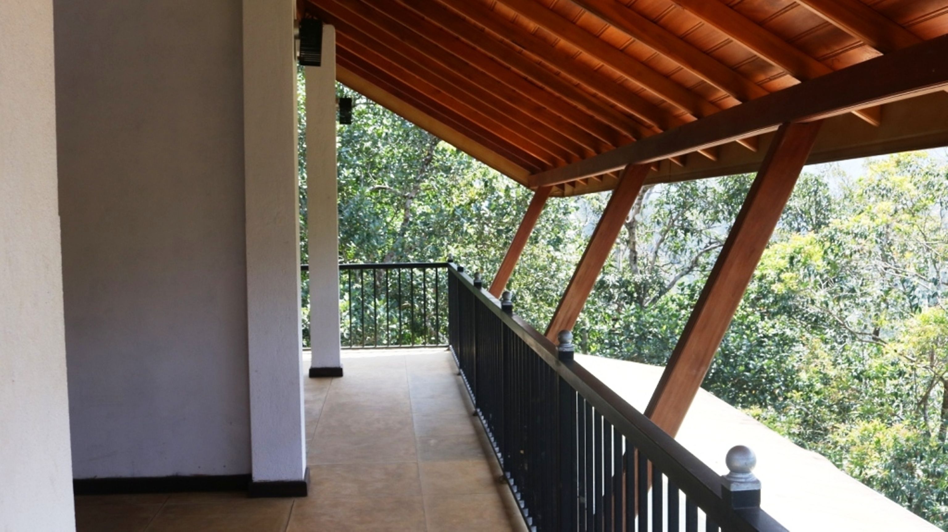 A covered balcony with a view of a forested area.