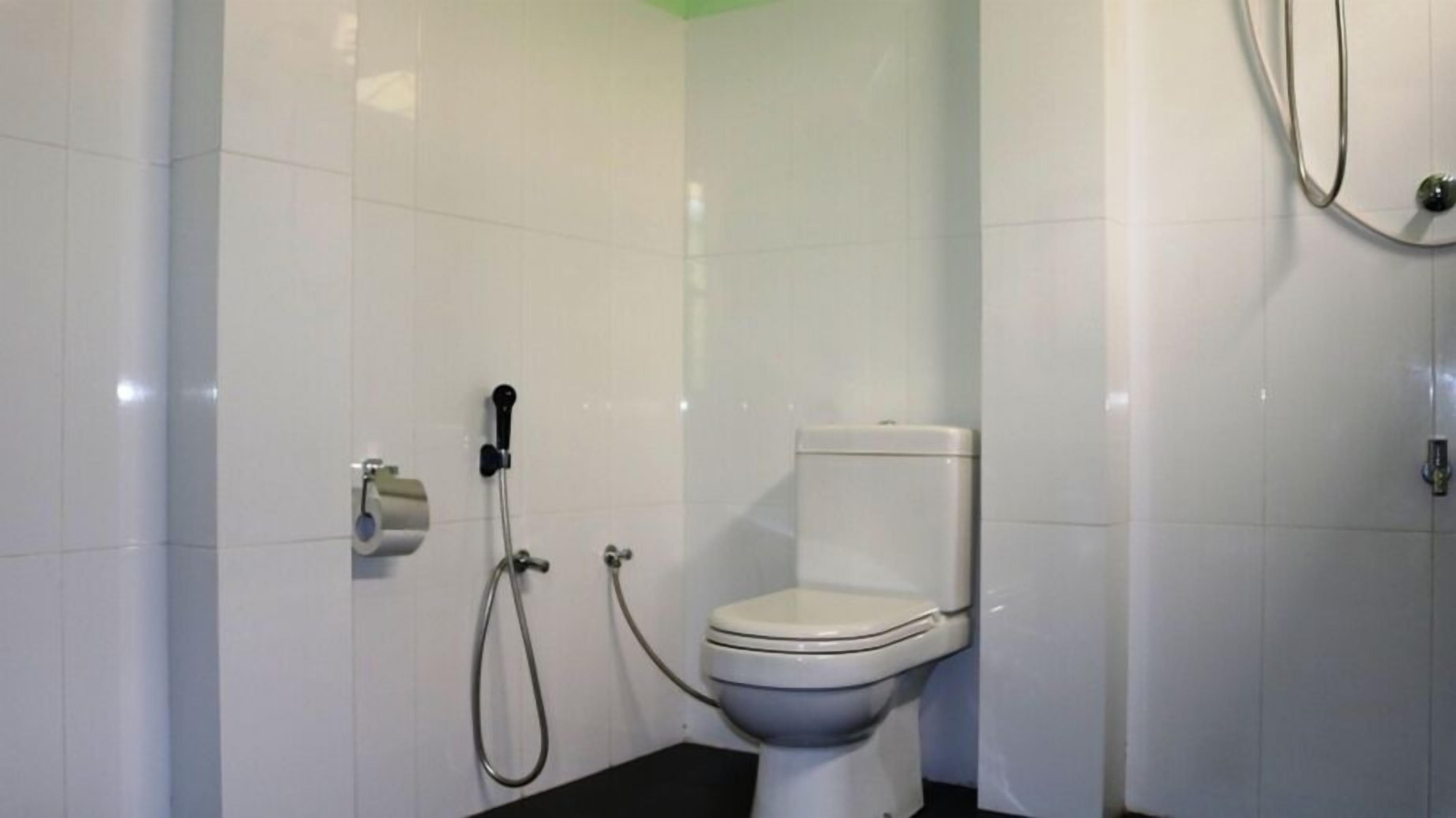 A small, white bathroom with a toilet, a shower, and a toilet paper holder.