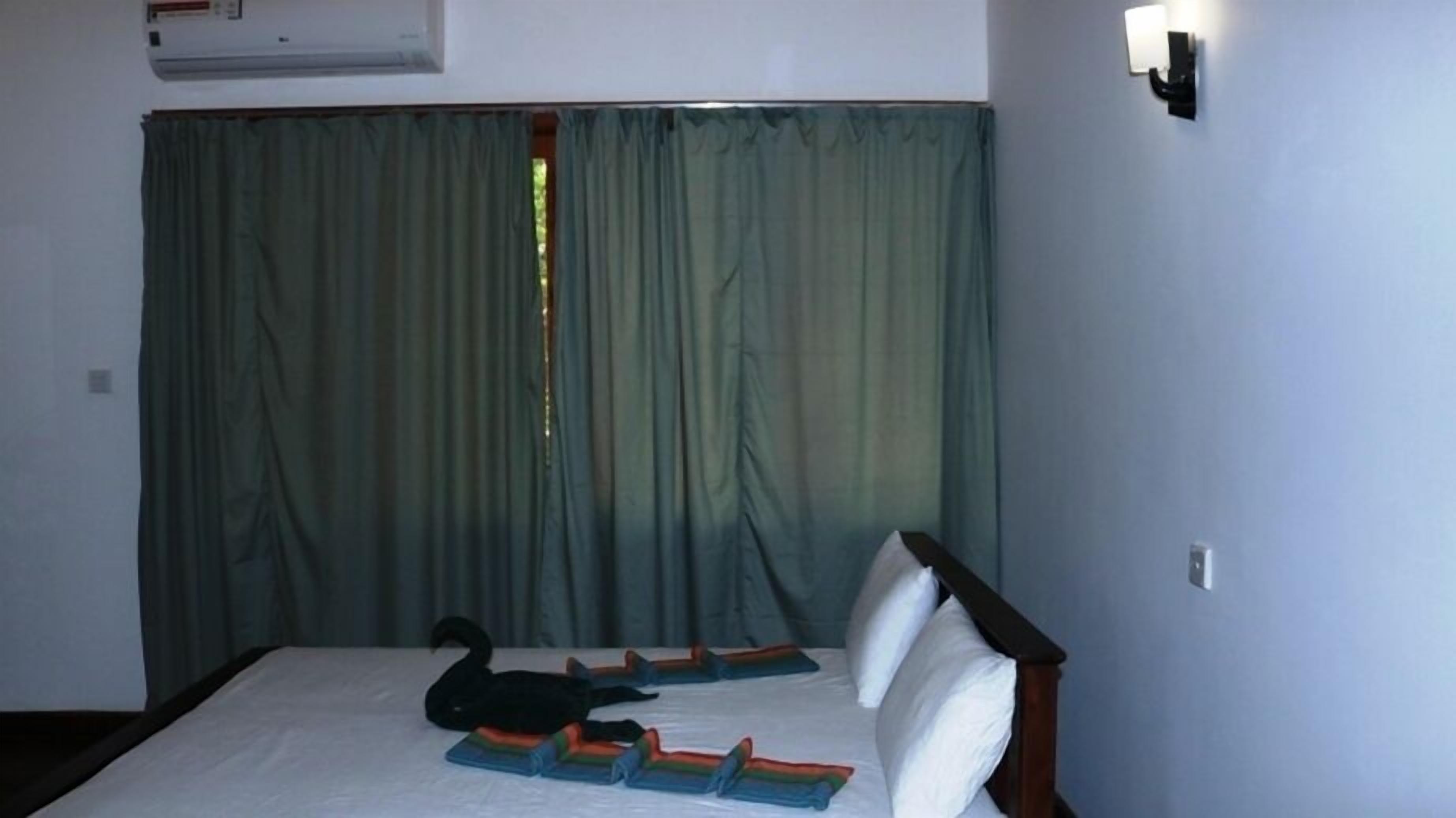 Una habitación con cama, una decoración de cisne negro y una ventana con cortinas.