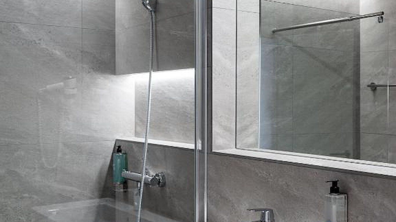 A modern bathroom with a glass shower enclosure, a visible towel rack, and a mirror reflecting the shower area.