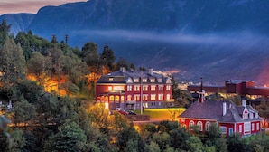 Un hôtel à la façade rouge, doté de nombreuses fenêtres et offrant une vue sur les montagnes en arrière-plan.