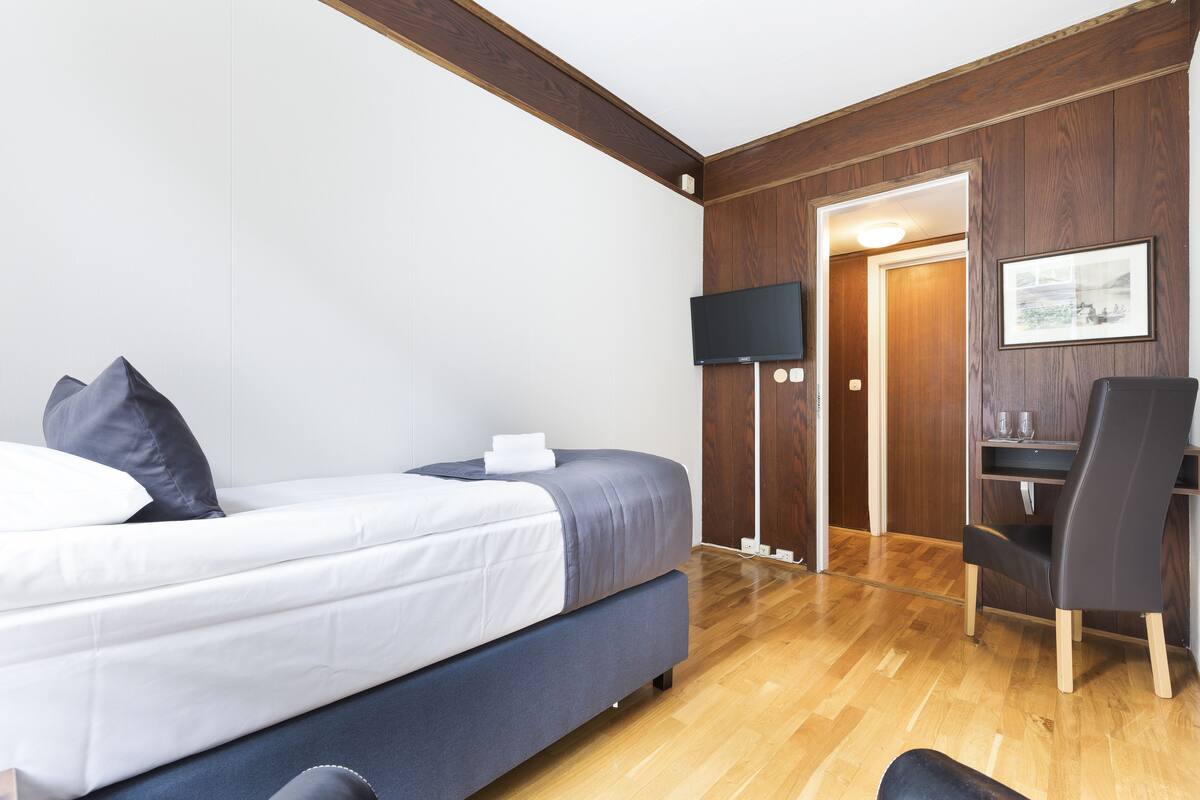 Une chambre d’hôtel moderne équipée d’un lit, d’un bureau et d’une télévision.