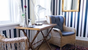 Una habitación con una mesa de madera, sillas de mimbre, un tapete estampado y papel tapiz a rayas.