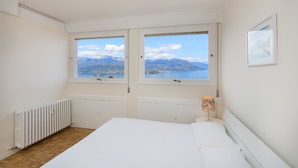 A bedroom with two windows offering a mountain and lake view. - Impero House Rent - Miralago (Stresa)