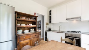 A kitchen with white cabinets, a wooden table, and a built-in oven. - Impero House Rent - Miralago (Stresa)