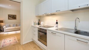 Une cuisine moderne avec des meubles blancs, un évier en acier inoxydable et un four.