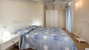 Une chambre à coucher comprenant un lit, une table de chevet, une armoire et un luminaire suspendu.