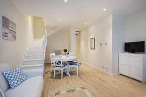 Ein modernes Wohnzimmer mit Treppe, Essbereich und Fernsehschrank.