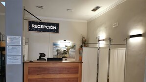 A reception desk with a wooden finish, a sign above it reading "RECEPCIÓN", and a framed artwork depicting two figures by the sea. - Hotel Costa Andaluza (Motril)