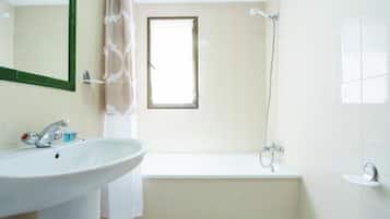 Een badkamer met een wastafel, spiegel, douche en bad.