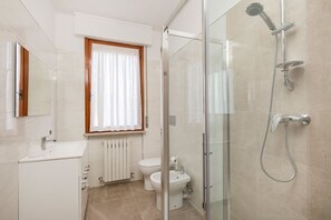 A modern bathroom with a glass shower enclosure, a toilet, a bidet, and a sink. - Impero House Rent - D'Azeglio (Stresa)