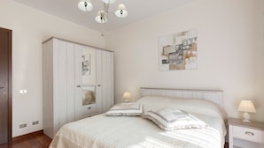 Une chambre à coucher comprenant un lit, des tables de chevet, une armoire et un luminaire au plafond.