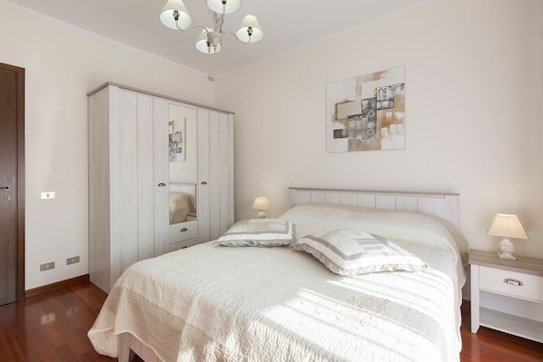 A bedroom with a bed, bedside tables, a wardrobe, and a ceiling light fixture.