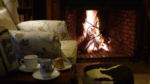 A cozy room with a fireplace, a sofa, a table with a teapot and a cup, and a decorative pillow. - Rondo Retreat Centre (Kakamega)