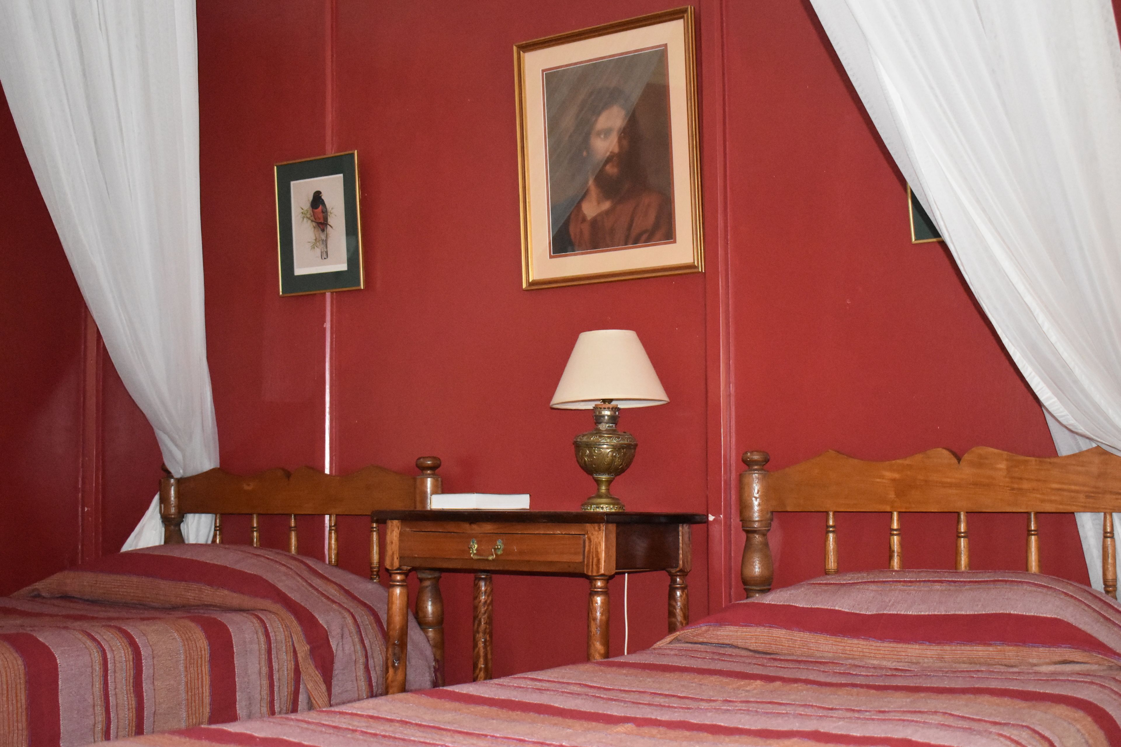 Un dormitorio con dos camas, una mesita de noche, una lámpara y un cuadro en la pared.