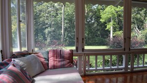 A room with a large window, a wooden floor, and a bed with striped bedding. - Rondo Retreat Centre (Kakamega)