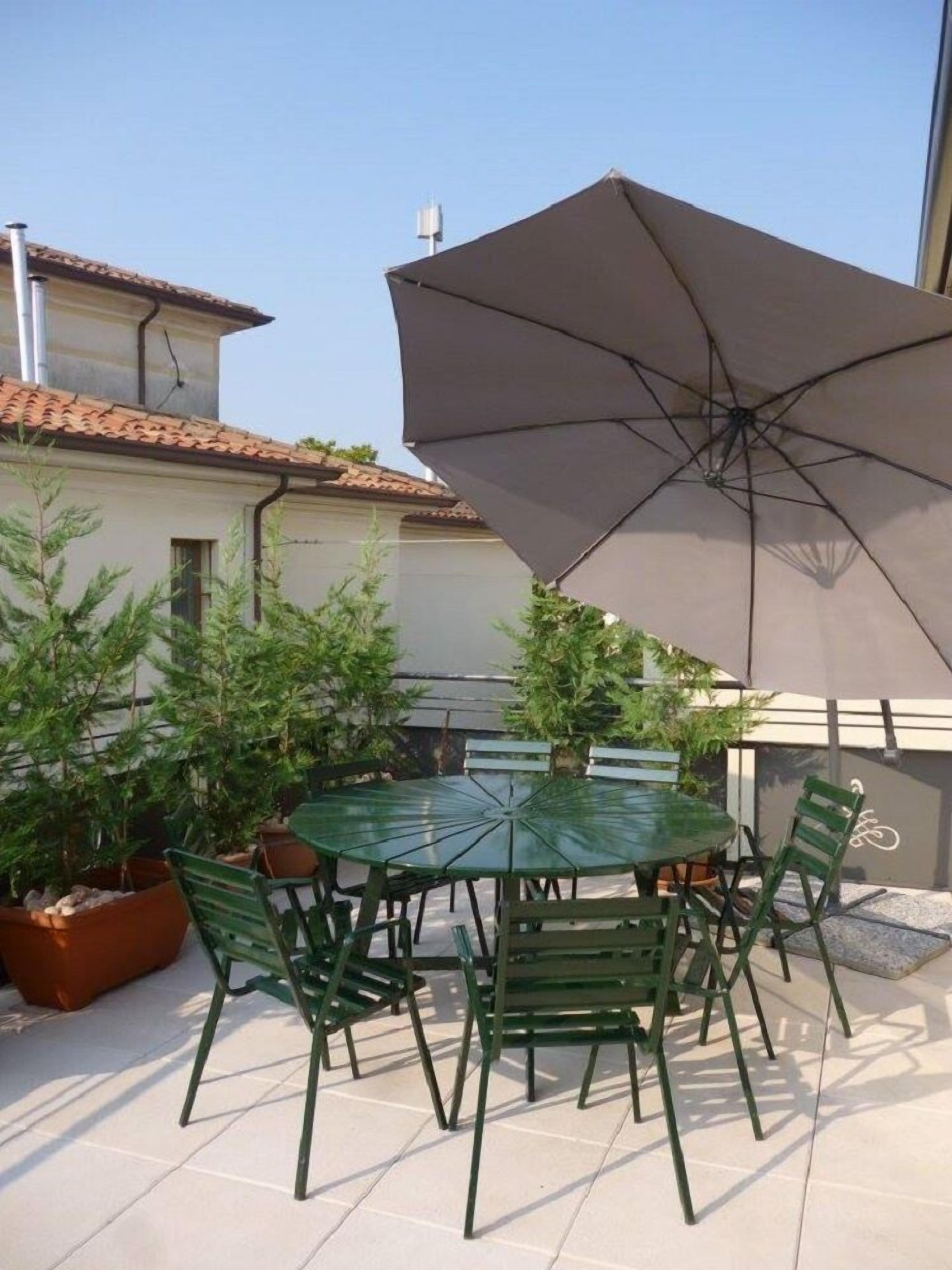 An outdoor patio with a round table and chairs, surrounded by potted plants.