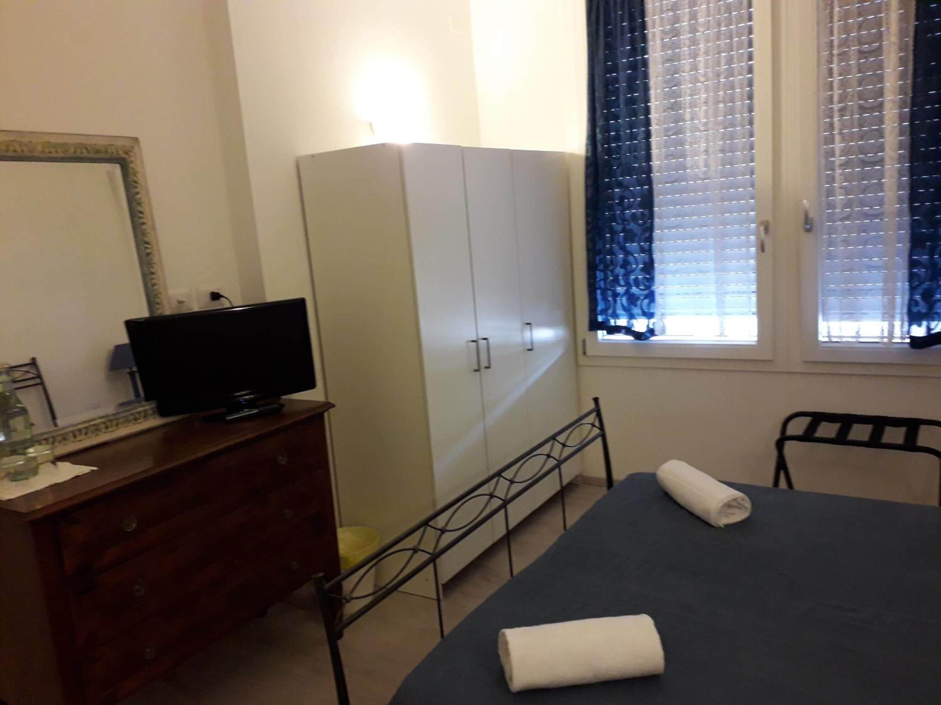 Un dormitorio con una cama, un aparador, un televisor y un armario.